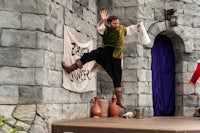 a man jumping on a stage in front of a castle